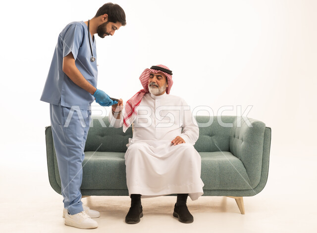 جهاز قياس سكر الدم لمرضى السكري، العمل في القطاع الطبي وشركات التمريض المنزلي، الرعاية الصحية والفحص الطبي السريع، بورتريه لممرض يرتدي المعطف الطبي يقوم بفحص نسبة السكر في الدم لمريض مسن عربي خليجي سعودي يرتدي الشماغ والثوب التقليدي يجلس على الكنبه، خلفية بيضاء