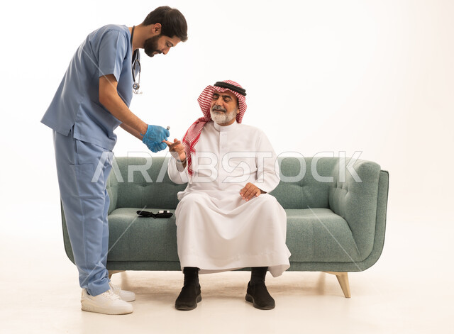جهاز قياس سكر الدم لمرضى السكري، العمل في القطاع الطبي وشركات التمريض المنزلي، الرعاية الصحية والفحص الطبي السريع، بورتريه لممرض يرتدي المعطف الطبي يقوم بفحص نسبة السكر في الدم لمريض مسن عربي خليجي سعودي يرتدي الشماغ والثوب التقليدي يجلس على الكنبه، خلفية بيضاء