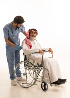 مفهوم الرعاية الصحية والاعتناء بالمرضى والمقعدين، نمط حياة ذوي الهمم، ايماءات السرور والسعادة، بورتريه لممرض يرتدي اليونيفورم والكمامة يقوم بالاعتناء برجل عربي خليجي سعودي مقعد يرتدي الثوب التقليدي والشماغ يجلس على كرسي متحرك، صورة لكامل الجسم، خلفية بيضاء