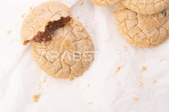 Picture of pieces of crispy biscuits scattered on a white background, pieces of biscuits stuffed with chocolate chips.