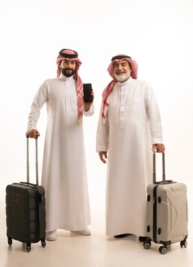 عرض شاشة هاتف محمول سوداء فارغة, قضاء أوقات ممتعة في الإجازة برفقة العائلة, الاستمتاع بالسفر و الرحلات الصيفية, بورتريه لرجل عربي خليجي سعودي كبير في السن يرتدي الثوب التقليدي والشماغ يمسك بيده حقيبة السفر يقف بجانب ابنه, صورة للجسم بالطول الكامل, خلفية بيضاء