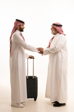 الاستقبال والتوديع عند السفر, القاء التحية والسلام, قضاء أوقات ممتعة في الإجازة برفقة العائلة, بورتريه لرجل عربي خليجي سعودي كبير في السن يرتدي الثوب التقليدي والشماغ يمسك بيده حقيبة السفر يقف بجانب ابنه, صورة للجسم بالطول الكامل, خلفية بيضاء