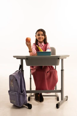 Eating a healthy breakfast during school break, enjoying healthy food during school break, back to school season, close-up portrait of a Saudi Arabian Gulf Arab female student wearing school uniform sitting at a desk, white background