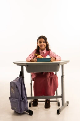  تناول وجبة الفطور الصحية في الفسحة المدرسية، الاستمتاع بتناول الأطعمة الصحية في وقت الفسحة المدرسية، موسم العودة للمدارس، بورتريه لطالبة عربيه خليجيه سعودية ترتدي الزي المدرسة تجلس على الطاوله المكتبية، خلفية بيضاء