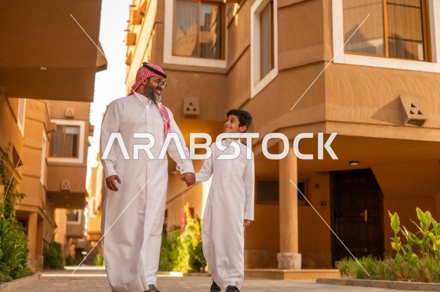 ايماءات وجه وايدي تعبر عن المحبة، أجواء أسرية مليئة بالمودة، عائلة تقف عند مدخل منزل عصري ، طفل يرتدي الثوب الأبيض، قضاء وقت ممتع مع الأطفال, مشاركة اللحظات السعيدة والتسلية مع الأبناء,أب عربي خليجي سعودي يمسك بيد ابنه ويلعب معه, مفهوم الأسرة السعيدة