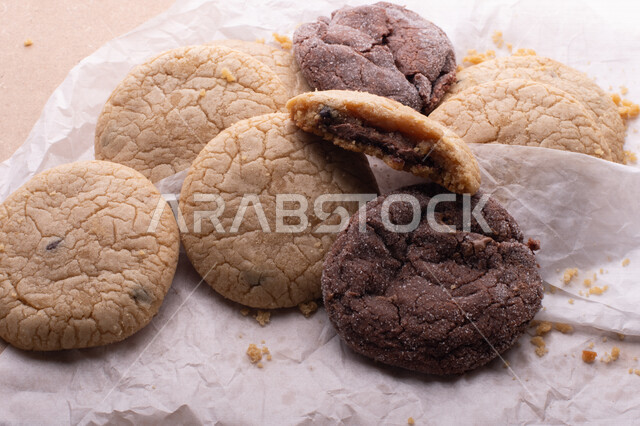 صورة لقطع من البسكويت المقرمش متناثر على الطاولة , قطع البسكويت المحشوة بقطع الشوكولاتة  . 
