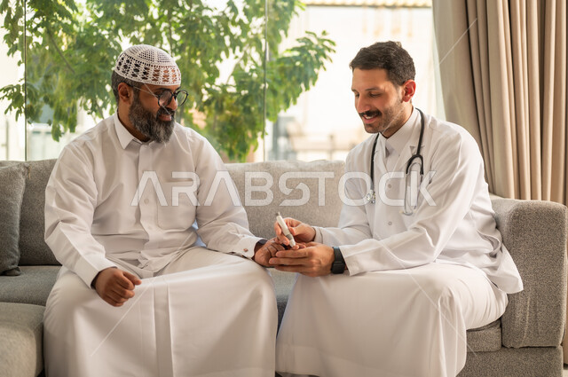 جهاز قياس سكر الدم لمرضى السكري، العمل في القطاع الطبي وشركات التمريض المنزلي، الرعاية الصحية والفحص الطبي السريع, ممرض يرتدي المعطف الطبي يقوم بفحص نسبة السكر في الدم لمريض مسن عربي خليجي سعودي يرتدي الشماغ والثوب التقليدي يجلس على الكنبه