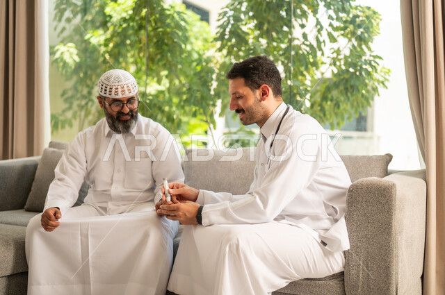 جهاز قياس سكر الدم لمرضى السكري، العمل في القطاع الطبي وشركات التمريض المنزلي، الرعاية الصحية والفحص الطبي السريع, ممرض يرتدي المعطف الطبي يقوم بفحص نسبة السكر في الدم لمريض مسن عربي خليجي سعودي يرتدي الشماغ والثوب التقليدي يجلس على الكنبه