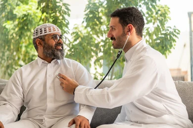 Heart rate measurement, concept of medicine and healthcare, periodic follow-up to check heart rate, a Saudi Arabian Gulf doctor wearing a medical coat using a stethoscope on an elderly patient
