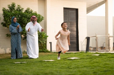  المحافظة على الترابط الأسري، الاعتناء والاهتمام بالاولاد, اللعب والتسلية والترفيه مع العائلة في الهواء الطلق, قضاء أوقات ممتعه مع الأهل الأبناء، زوجان عربيان خليجيان سعوديان يلعبان في الحديقة مع ابنتهما بإيماءات السعادة