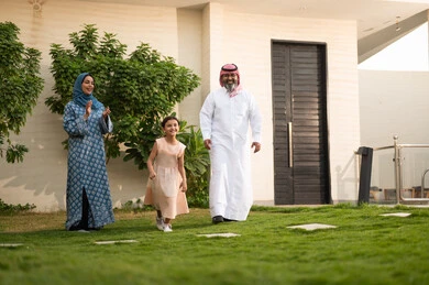  المحافظة على الترابط الأسري، الاعتناء والاهتمام بالاولاد, اللعب والتسلية والترفيه مع العائلة في الهواء الطلق, قضاء أوقات ممتعه مع الأهل الأبناء، زوجان عربيان خليجيان سعوديان يلعبان في الحديقة مع ابنتهما بإيماءات السعادة