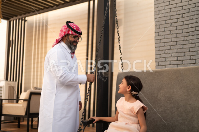 الإستمتاع باللعب في يوم مشمس, قضاء وقت ممتع في الخارج، فتاة عربيه سعوديه خليجيه مبتسمة تلعب في المنتزه بتعابير السرور والسعادة برفقة والدها, التأرجح على الأرجوحه
