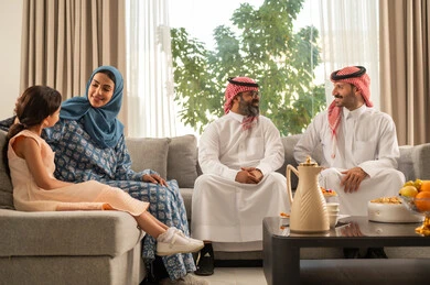 The joy and happiness of children on the happy Eid days, family gatherings and visits on Islamic holidays and occasions, a Saudi Arabian Gulf man wearing traditional clothing sitting with his grandchildren with gestures of joy and happiness, Eid hospitality and sweets, good reception and hospitality of guests, kinship ties and family bonds