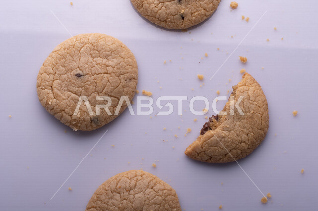 صورة لقطع من البسكويت المقرمش متناثر على الطاولة , قطع البسكويت المحشوة بقطع الشوكولاتة  . 