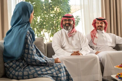 The joy and happiness of children on the happy Eid days, family gatherings and visits on Islamic holidays and occasions, a Saudi Arabian Gulf man wearing traditional clothing sitting with his grandchildren with gestures of joy and happiness, Eid hospitality and sweets, good reception and hospitality of guests, kinship ties and family bonds