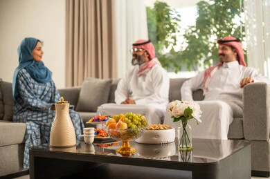 حسن استقبال وإكرام الضيف، صلة الرحم والترابط الاسري, فرحة وبهجة الابناء في ايام العيد السعيد, التجمعات والزيارات الاسرية في الأعياد والمناسبات الاسلامية, رجل عربي خليجي سعودي يرتدي الثوب التقليدي يجلس مع أحفاده بإيماءات الفرح والسرور, ضيافة وحلوى العيد