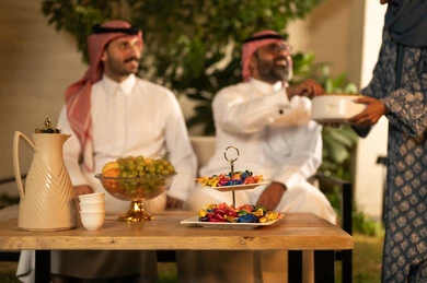 صلة الرحم والترابط الاسري, فرحة وبهجة الابناء في ايام العيد السعيد, التجمعات والزيارات الاسرية في الأعياد والمناسبات الاسلامية, عائلة عربية خليجية سعودية تجلس في الخارج ببإيماءات الفرح والسرور، ضيافة وحلوى العيد، حسن استقبال وإكرام الضيف