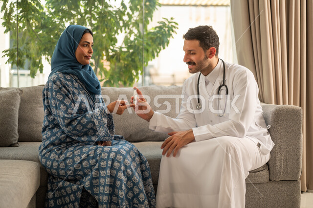 المتابعة الدورية لمرضى داء السكري, الفحوصات الطبية السريعة لمعرفة نسبة السكر في الدم، استخدام الأجهزة الالكترونية للتحاليل المنزلية، شابة سعودية مصابة بحالة مرضية مزمنة, طبيب عربي خليجي سعودي يرتدي المعطف الطبي يقوم بوخز اصبع امرأة