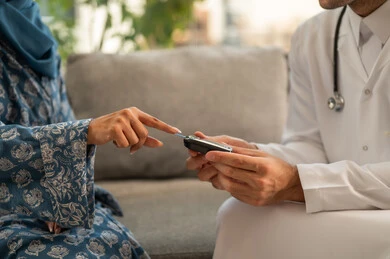 الفحوصات الطبية السريعة لمعرفة نسبة السكر في الدم، استخدام الأجهزة الالكترونية للتحاليل المنزلية، شابة سعودية مصابة بحالة مرضية مزمنة, طبيب عربي خليجي سعودي يرتدي المعطف الطبي يقوم بوخز اصبع امرأة, المتابعة الدورية لمرضى داء السكري