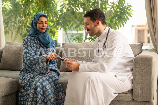 المتابعة الدورية لمرضى داء السكري, الفحوصات الطبية السريعة لمعرفة نسبة السكر في الدم، استخدام الأجهزة الالكترونية للتحاليل المنزلية، شابة سعودية مصابة بحالة مرضية مزمنة, طبيب عربي خليجي سعودي يرتدي المعطف الطبي يقوم بوخز اصبع امرأة