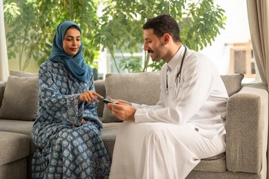 المتابعة الدورية لمرضى داء السكري, الفحوصات الطبية السريعة لمعرفة نسبة السكر في الدم، استخدام الأجهزة الالكترونية للتحاليل المنزلية، شابة سعودية مصابة بحالة مرضية مزمنة, طبيب عربي خليجي سعودي يرتدي المعطف الطبي يقوم بوخز اصبع امرأة