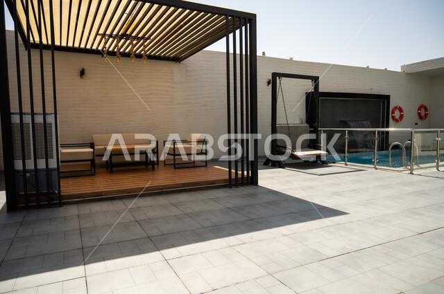A quiet outdoor seating area in front of the swimming pool, luxurious home furnishings in a chalet, modern interior design for seating areas, suites furnished with all the finest furnishings, elegant interior design for villas and residential apartments in the Kingdom of Saudi Arabia.