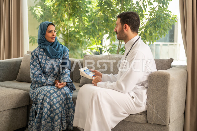 Using a modern and advanced electronic scale for quick home testing. A Saudi Arabian Gulf doctor wearing a medical coat measures a patient's blood pressure at home. The concept of health care and concern for physical health.