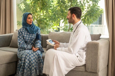 استخدام الميزان الالكتروني الحديث والمتطور للفحص المنزلي السريع,  طبيب عربي خليجي سعودي يرتدي المعطف الطبي يقوم بقياس ضغط الدم للمريضة في المنزل, مفهوم الرعاية الصحية والاهتمام بالصحة الجسدية