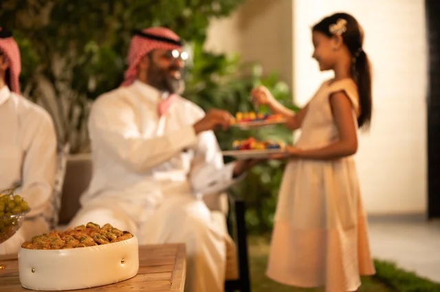 فرحة وبهجة الابناء في ايام العيد السعيد, التجمعات والزيارات الاسرية في الأعياد والمناسبات الاسلامية, رجل عربي خليجي سعودي يرتدي الثوب التقليدي يجلس مع أحفاده بإيماءات الفرح والسرور، ضيافة وحلوى العيد، حسن استقبال وإكرام الضيف، صلة الرحم والترابط الاسري