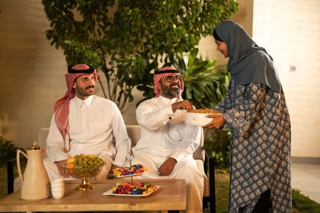 فرحة وبهجة الابناء في ايام العيد السعيد, التجمعات والزيارات الاسرية في الأعياد والمناسبات الاسلامية, رجل عربي خليجي سعودي يرتدي الثوب التقليدي يجلس مع أحفاده بإيماءات الفرح والسرور، ضيافة وحلوى العيد، حسن استقبال وإكرام الضيف، صلة الرحم والترابط الاسري