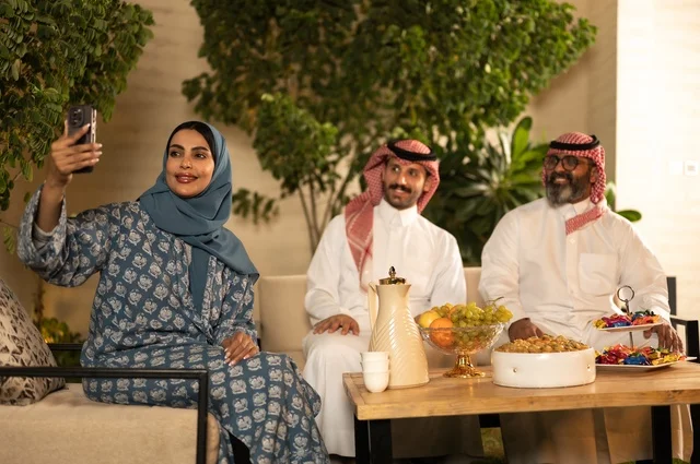 التقاط صورة سيلفي عبر الهاتف المحمول، ضيافة وحلوى العيد، حسن استقبال وإكرام الضيف، فرحة وبهجة الابناء في ايام العيد السعيد, التجمعات والزيارات الاسرية في الأعياد والمناسبات الاسلامية, رجل عربي خليجي سعودي يرتدي الثوب التقليدي يجلس مع أحفاده بإيماءات الفرح والسرور