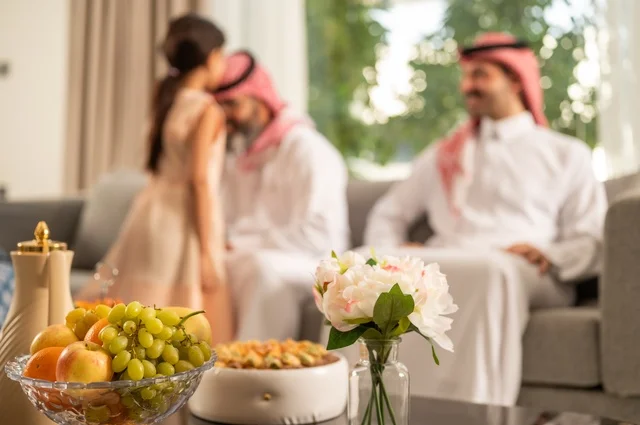 ضيافة وحلوى العيد، حسن استقبال وإكرام الضيف، صلة الرحم والترابط الاسري, فرحة وبهجة الابناء في ايام العيد السعيد, التجمعات والزيارات الاسرية في الأعياد والمناسبات الاسلامية, رجل عربي خليجي سعودي يرتدي الثوب التقليدي يجلس مع أحفاده بإيماءات الفرح والسرور
