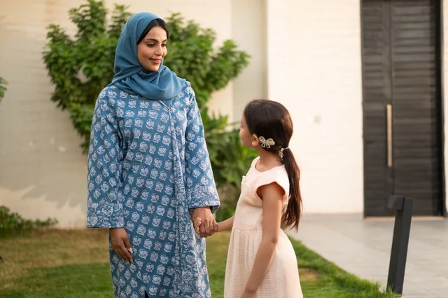 شاليه ومنتجع ترفيهي في المملكة، الاستمتاع بالإجازة الصيفية برفقة العائلة، ايماءات السعادة والسرور، قضاء وقت ممتع ومنعش في فصل الصيف، الأجواء العائلية المليئة بالحب، عائلة عربية خليجية سعودية مبتسمة تمشي في المنتزه