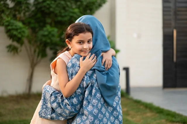 A mother hugging her daughter, a chalet and a recreational resort in the Kingdom, enjoying the summer vacation with the family, gestures of happiness and pleasure, spending a fun and refreshing time in the summer, a family atmosphere full of love, a smiling Saudi Arabian Gulf family walking in the park