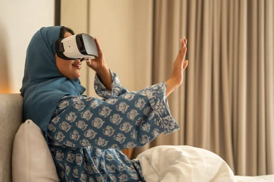 Simulating a fantasy world, entertainment by watching through virtual reality glasses, a veiled Saudi Arabian Gulf woman wearing an abaya looking through 3D glasses, trying to touch something with expressions of integration