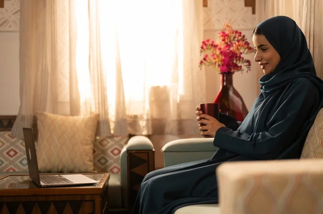 قضاء الوقت باحتساء المشروب المفضل, الحيوية والنشاط عن شرب الكافئيين, الاستمتاع بالمشروبات الساخنة والأعشاب الشتوية الدافئة, شابة عربية خليجية سعودية ترتدي العباءة والحجاب تمسك كوب من القهوة و تستمتع بلحظات الهدوء والراحة