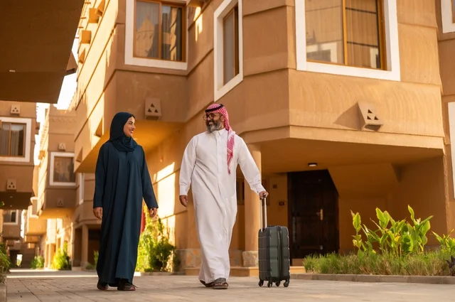 Spending an enjoyable summer trip, the concept of tourism during the summer vacation, an Arab Gulf couple from Saudi Arabia dragging luggage, expressions and gestures of happiness and joy, a family having a good time, preparing to travel on a tourist tour.