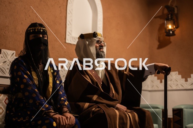 Gestures of pride and honor in the Saudi identity, the anniversary of the establishment of the first Saudi state in 1727 AD, an Arab Gulf couple wearing traditional attire during holidays and national occasions sitting in one of the heritage houses in the old style, the concept of love for the homeland and belonging to it.