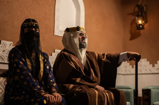 إيماءات الاعتزاز و الفخر بالهوية السعودية، ذكرى تأسيس الدولة السعودية الأولى 1727 م، زوجان عربيان خليجيان سعوديان يرتديان الأزياء الشعبية في الأعياد والمناسبات الوطنية يجلسان في إحدى البيوت التراثية على الطراز القديم، مفهوم حب الوطن والانتماء اليه