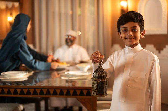 فانوس معدني مزخرف ملون،  أجواء عائلية دينية رمضانية سعيدة، تبادل الأحاديث بين أفراد الأسرة، عائلة عربية خليجية سعودية مجتمعة حول مائدة الطعام، سفرة مليئة بأصناف من المأكولات الشرقية الشهية، أداء فريضة الصيام في شهر رمضان المبارك