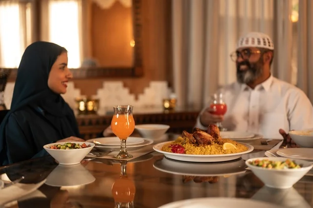 ايماءات السرور لاجتماع العائلة حول مائدة إفطار رمضان، أجواء عائلية روحانية دينية إسلامية، عائلة عربية خليجية سعودية مجتمعة حول مائدة الطعام، سفرة مليئة بأصناف من المأكولات الشرقية الشهية، أداء فريضة الصيام في شهر رمضان المبارك، موعد كسر الصيام عند الأذان