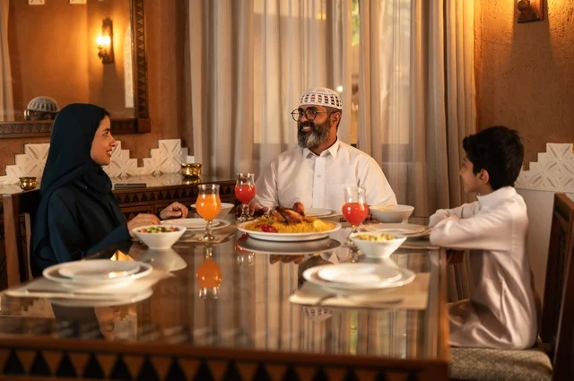 تبادل الأحاديث بين أفراد الأسرة، أجواء عائلية دينية رمضانية سعيدة، عائلة عربية خليجية سعودية مجتمعة حول مائدة الطعام، سفرة مليئة بأصناف من المأكولات الشرقية الشهية، أداء فريضة الصيام في شهر رمضان المبارك، زينة المناسبات الإسلامية
