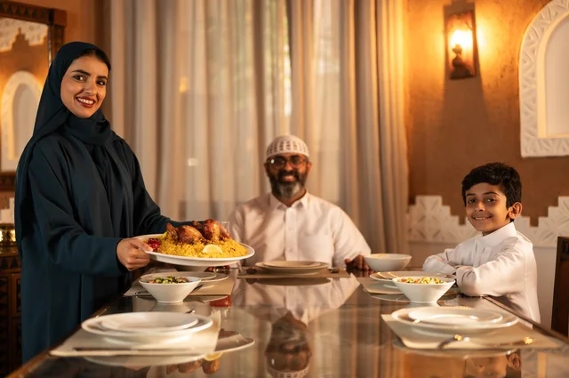 أجواء عائلية روحانية دينية إسلامية، ايماءات السرور لاجتماع العائلة حول مائدة إفطار رمضان، عائلة عربية خليجية سعودية مجتمعة حول مائدة الطعام، سفرة مليئة بأصناف من المأكولات الشرقية الشهية، أداء فريضة الصيام في شهر رمضان المبارك، موعد كسر الصيام عند الأذان
