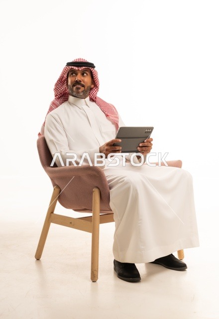 الدردشة مع الأهل والأصدقاء، استعمال التكنولوجيا والتقنيات الحديثة، بورتريه لرجل عربي خليجي عماني يرتدي الثوب والشماغ التقليدي يحمل بيده جهاز التابلت، تصفح مواقع التواصل الاجتماعي، استخدام تطبيقات وبرامج الأجهزة اللوحية، خلفية بيضاء