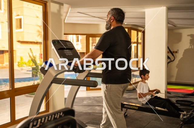 ممارسة تمارين الاحماء, المحافظة على الصحة واللياقة البدنية, شاب عربي خليجي سعودي يرتدي الملابس الرياضية يقوم بالمشي على الجهاز الكهربائي، نادي الألعاب الرياضية, القيام بالأنشطة الترفيهية الممتعة، استخدام الاجهزة الرياضية