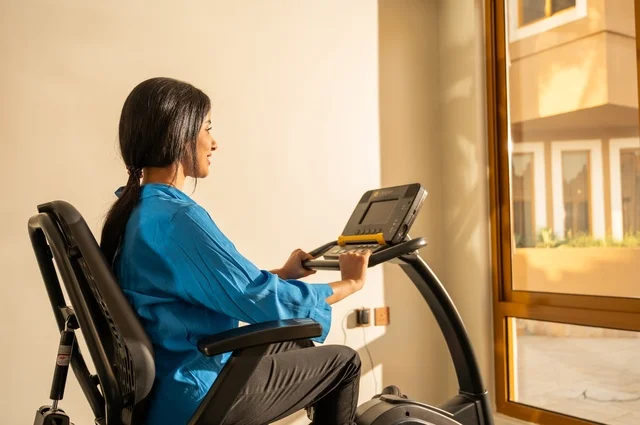 Physical activities to maintain fitness and agility, gestures of happiness and activity, following a healthy lifestyle using technological devices, sports to strengthen muscles and sculpt the body, a side image of a young Arab Gulf Saudi woman wearing sportswear exercising.