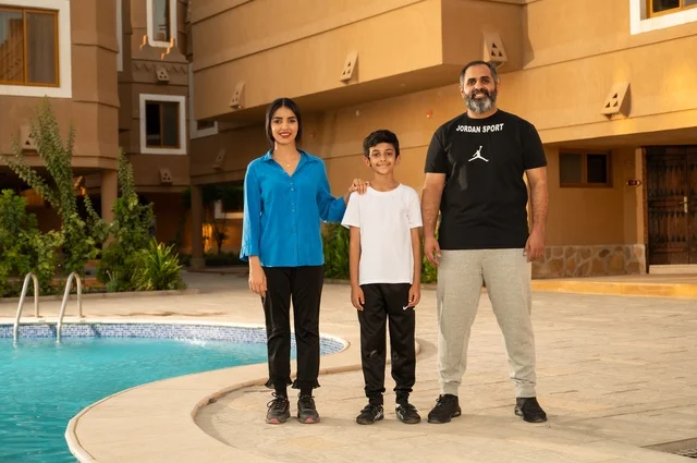 القيام بالأنشطة الترفيهية المسلية, مشاركة العائلة اللحظات الممتعة, قضاء العطلة الصيفية في المنتجعات السياحية, عائلة عربية خليجية سعودية تقف بجانب حوض السباحة في إحدى الفنادق بالسعودي، ممارسة رياضة السباحة الممتعة