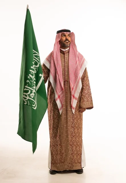 Flag Day is on March 11, wearing traditional clothing on national occasions, Saudi National Day is on September 23, pride and honor in the homeland, a portrait of an Arab Gulf Saudi man wearing a ghutrah and thobe holding the Saudi flag in his hand, the establishment of the Saudi Kingdom is on February 22, full-body image, white background.