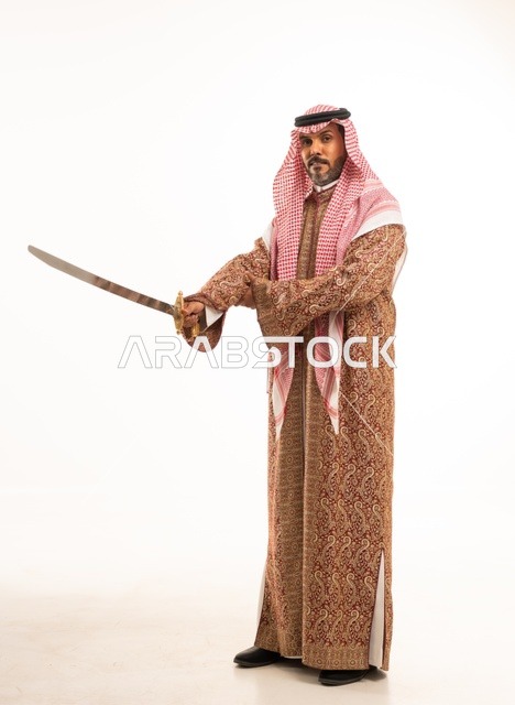 حمل السيف بتباهي وفخر احتفالا بيوم بدينا ١٧٢٧م، النظر إلى الكاميرا بإيماءات الاعتزاز، ارتداء الأزياء الشعبية في المناسبات الوطنية, بورتريه لرجل عربي خليجي سعودي يرتدي الشماغ والدقلة ، ذكرى تأسيس الدولة السعودية الأولى في 22 فبراير، صورة لكامل الجسم، خلفية بيضاء
