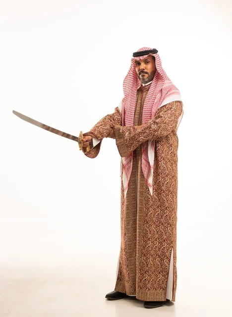 حمل السيف بتباهي وفخر احتفالا بيوم بدينا ١٧٢٧م، النظر إلى الكاميرا بإيماءات الاعتزاز، ارتداء الأزياء الشعبية في المناسبات الوطنية, بورتريه لرجل عربي خليجي سعودي يرتدي الشماغ والدقلة ، ذكرى تأسيس الدولة السعودية الأولى في 22 فبراير، صورة لكامل الجسم، خلفية بيضاء